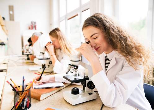 Women science students looking through microscopes