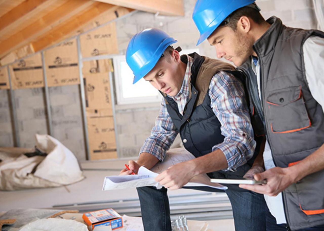 two construction workers review the plans