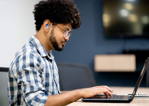 Hearing impaired man working on laptop at office