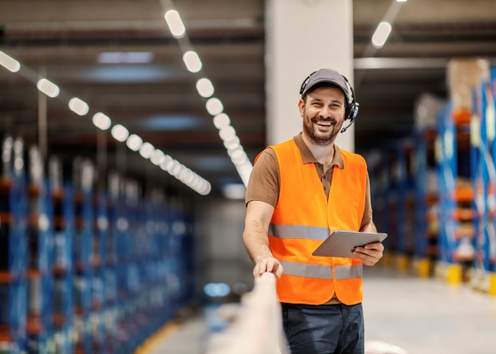 Portrait of a post express manager with voice picking headset holding tablet and smiling at camera